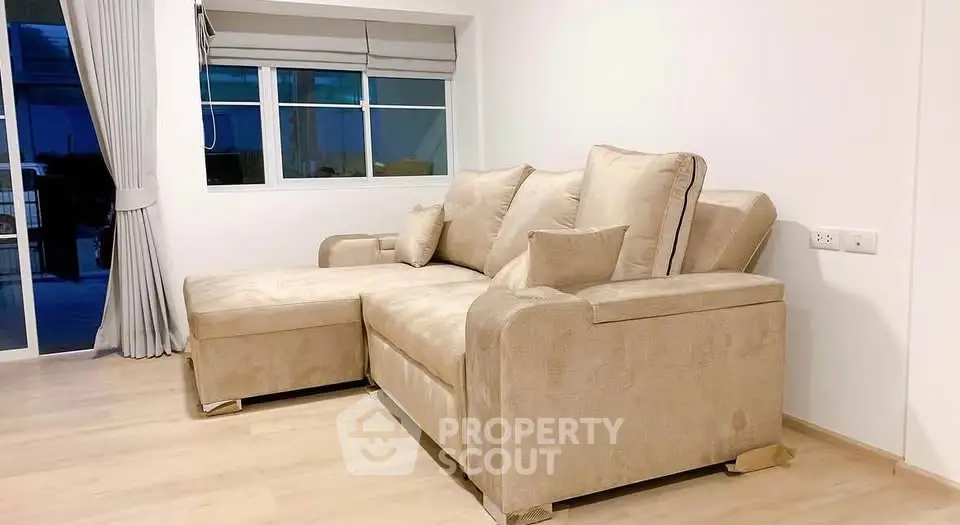 Spacious living room with elegant beige sectional sofa and large window for natural light.