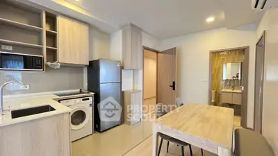 Modern kitchen with washing machine and dining area in open layout apartment.