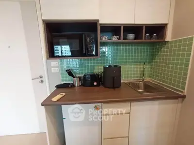 Compact kitchen with modern appliances and green tile backsplash