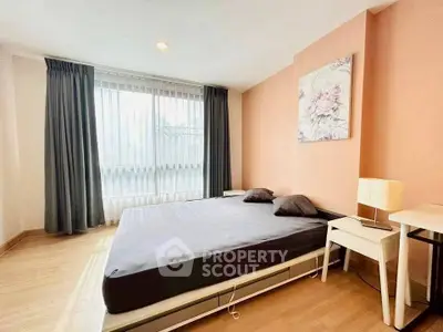 Spacious bedroom with large window and modern decor in a stylish apartment.