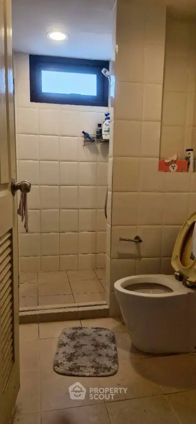 Cozy bathroom with shower and modern toilet in a tiled setting.