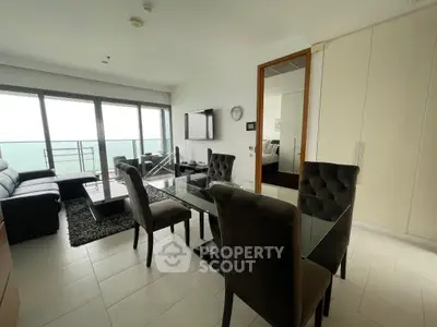 Modern living room with ocean view, glass dining table, and stylish furniture in a high-rise apartment.