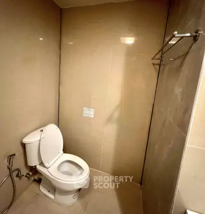 Modern bathroom with sleek beige tiles and a clean toilet setup.