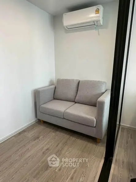 Cozy small living room with modern gray sofa and air conditioning unit.