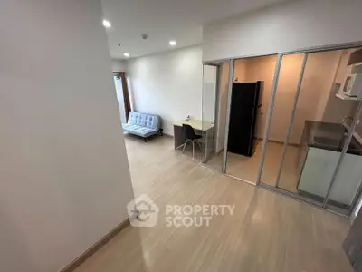 Modern apartment with open layout, featuring a cozy living area and sleek kitchen with glass partition.