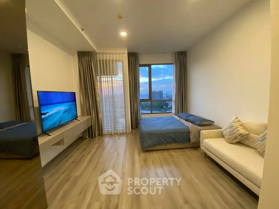 Modern living room with large window and city view, featuring sleek flooring and contemporary furniture.