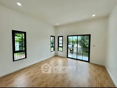 Spacious empty room with large windows and wooden flooring