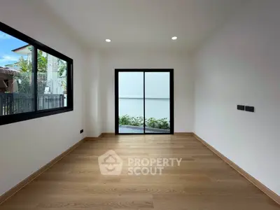 Spacious empty room with large windows and wooden flooring, perfect for customization.