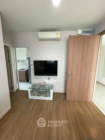Modern living room with wooden flooring, wall-mounted TV, and air conditioning unit.