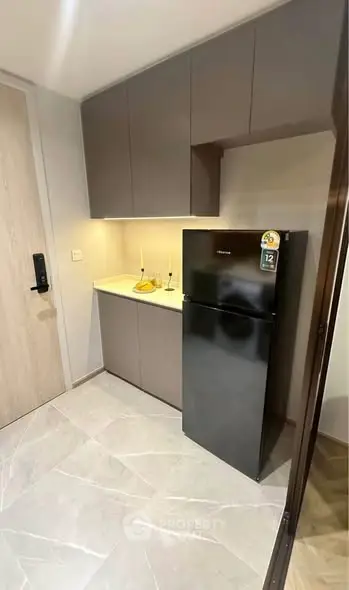 Modern kitchen with sleek cabinets and black fridge in compact space