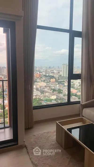 Stunning city view from modern high-rise apartment living room with large windows.
