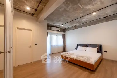 Modern industrial-style bedroom with exposed concrete ceiling and elegant wooden flooring.