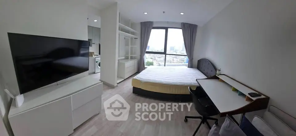 Modern bedroom with large window and city view, featuring a sleek TV and stylish desk.