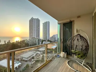 Stunning balcony view with sunset over the ocean and city skyline, featuring modern outdoor seating.
