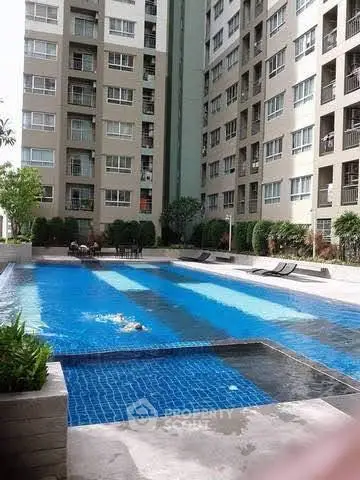 Modern apartment complex with inviting swimming pool and sun loungers.