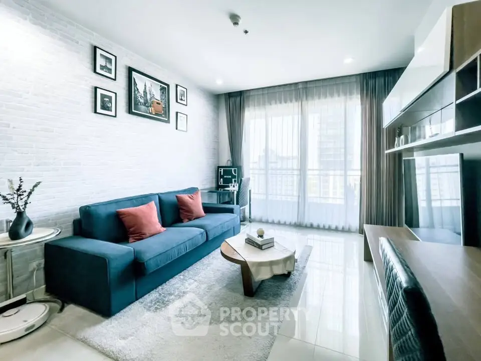 Modern living room with stylish decor, large windows, and cozy seating in a bright apartment.