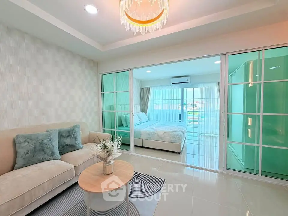 Modern living room with elegant decor and view into a cozy bedroom through sliding glass doors.
