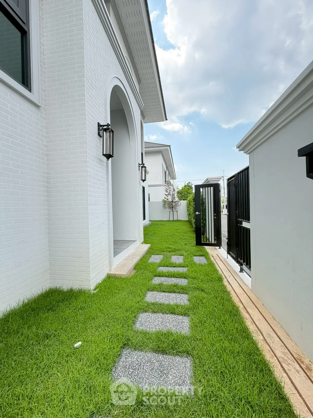 Charming modern home exterior with lush green lawn and stylish pathway leading to entrance.