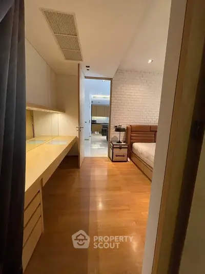 Spacious bedroom with wooden flooring and modern furnishings, featuring a cozy bed and ample storage space.