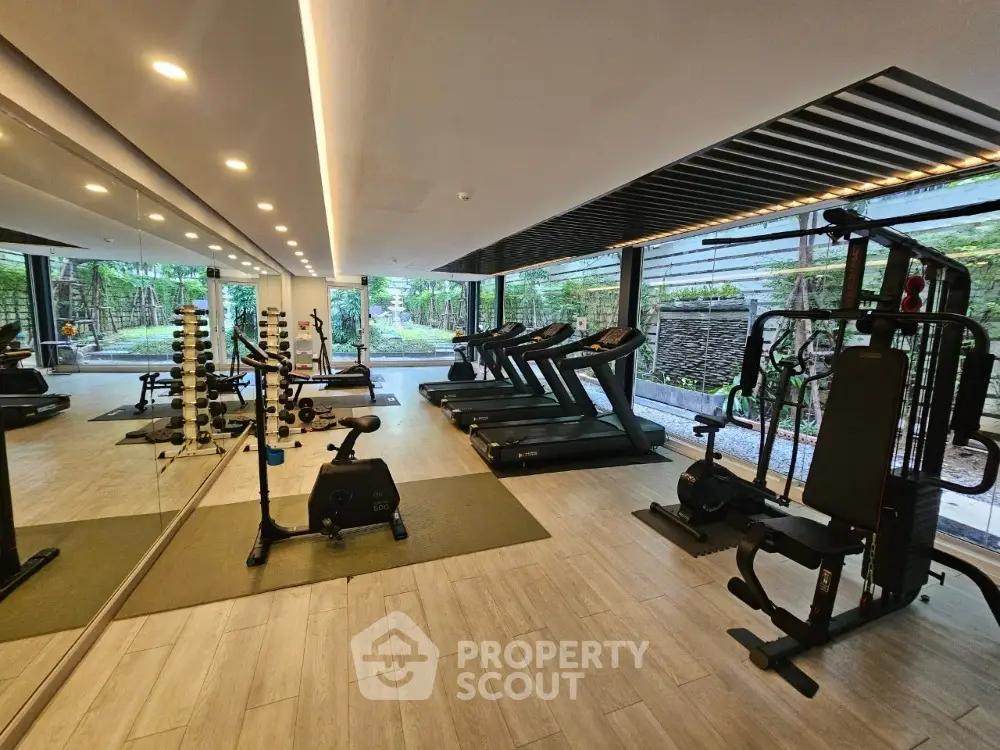 Modern gym with state-of-the-art equipment and garden view in luxury residential complex.