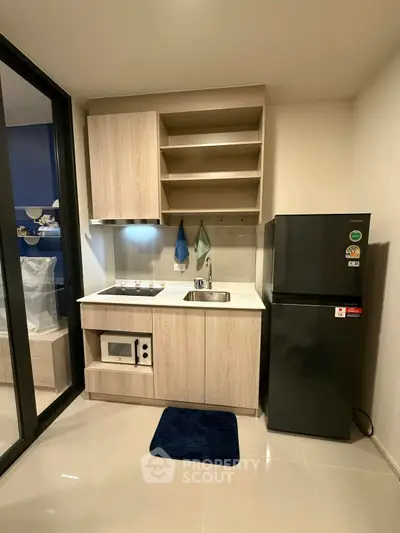 Modern compact kitchen with sleek cabinetry and appliances in a stylish apartment.