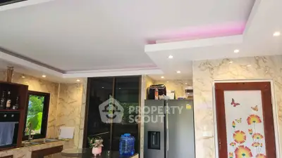 Modern kitchen with sleek design, featuring stainless steel fridge and elegant lighting.