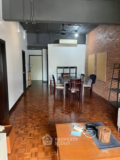 Spacious industrial-style living room with brick wall and wooden flooring
