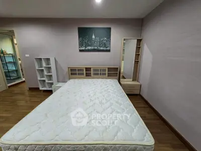 Spacious bedroom with wooden flooring and modern furniture, ideal for cozy living.