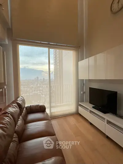 Spacious living room with leather sofa and city view through large window.