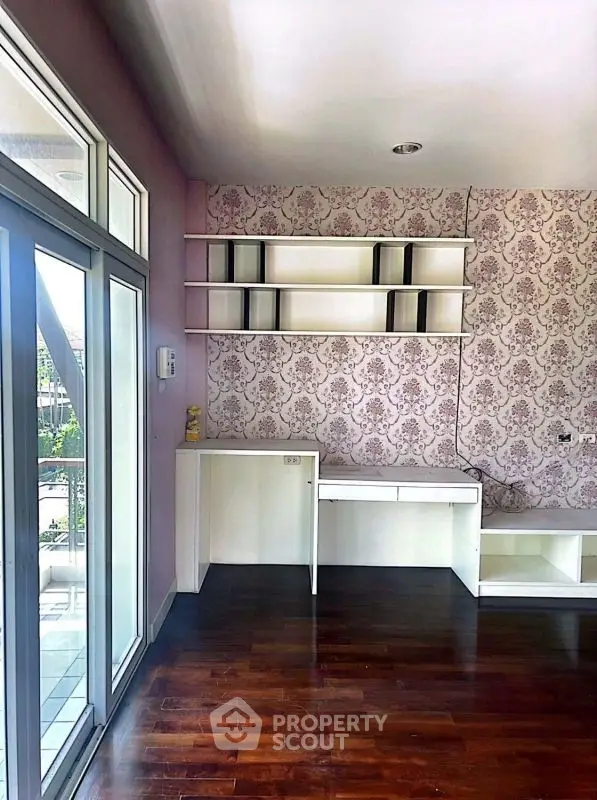 Chic study room with elegant wallpaper and built-in desk, featuring large windows for natural light.