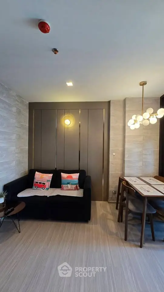 Modern living room with stylish decor and dining area, featuring contemporary lighting and cozy seating.