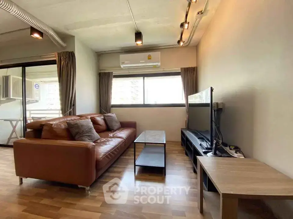 Spacious living room with modern decor and large window in urban apartment.