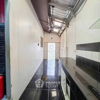 Sleek modern kitchen with glossy black tiles and ample natural light.