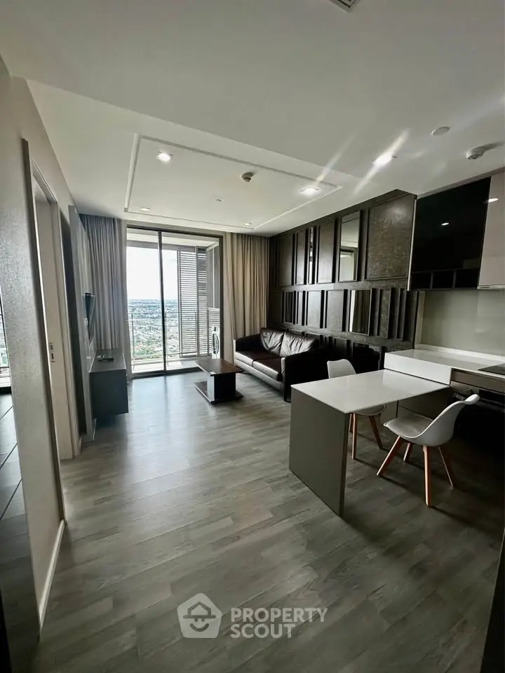 Modern living room with open kitchen and stunning city view from balcony.