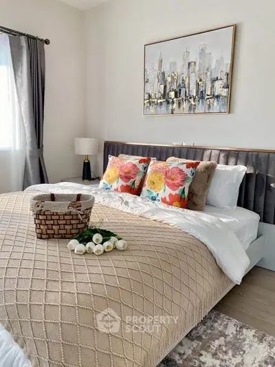 Cozy bedroom with stylish decor and natural light, featuring a plush bed and elegant artwork.