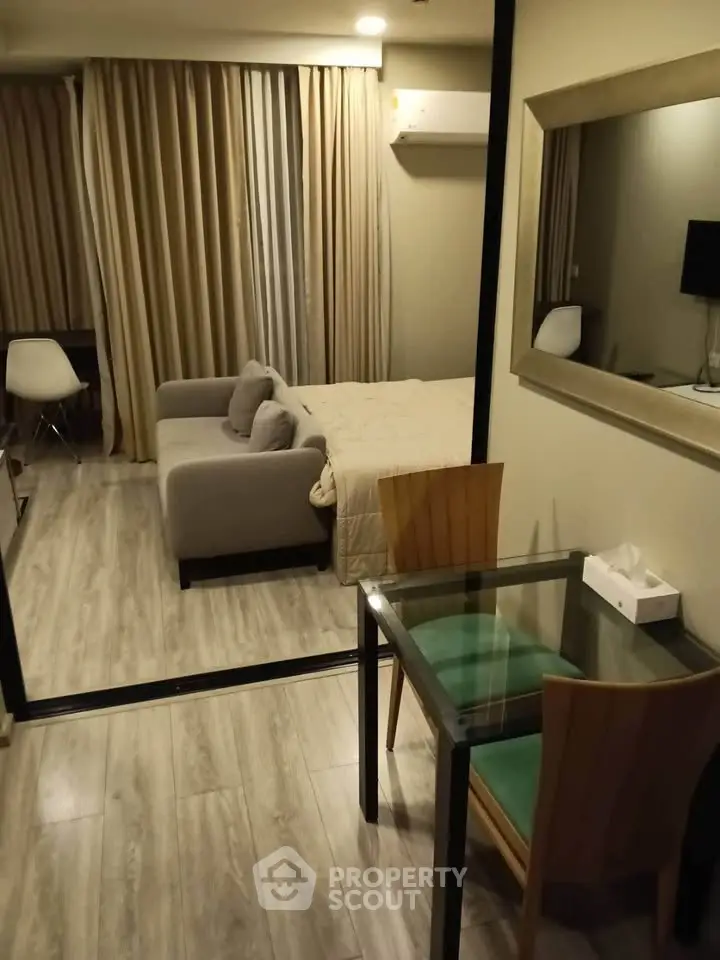 Cozy studio apartment with modern furnishings and wooden flooring, featuring a comfortable sofa and dining area.