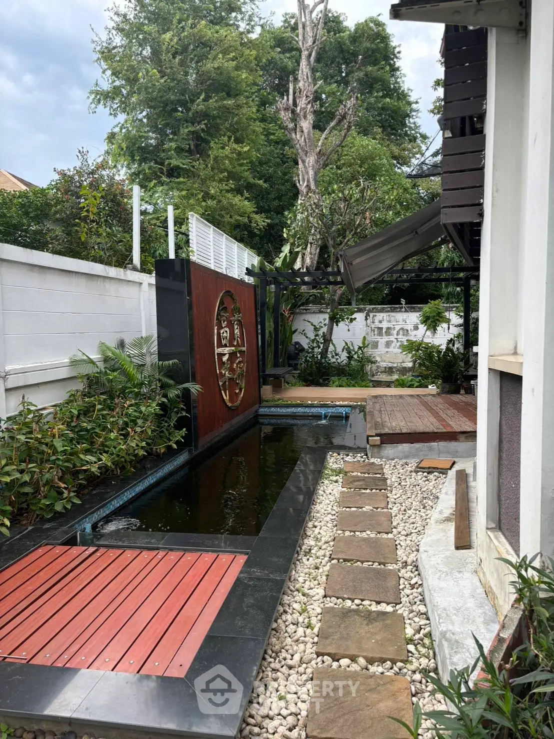 Charming garden with water feature and wooden deck in serene residential setting.