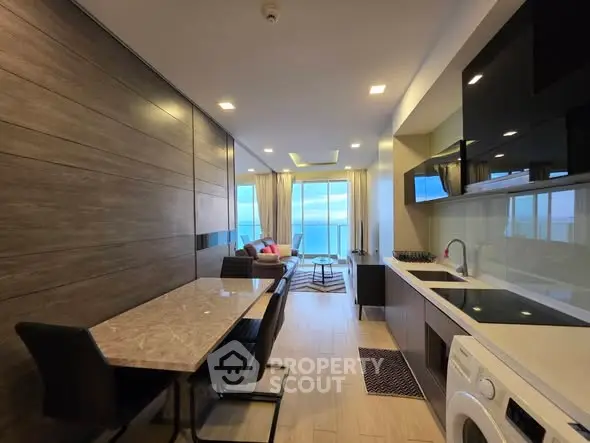 Modern open-layout kitchen and living room with ocean view, sleek furnishings, and natural light.