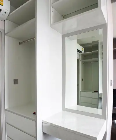 Modern walk-in closet with sleek white shelving and built-in mirror