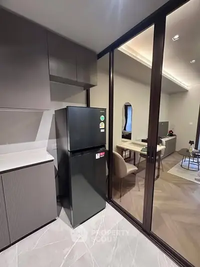 Modern kitchen with sleek design and glass partition leading to stylish living area.