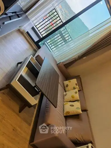 Cozy living room with modern furniture, hardwood floors, and access to a sunlit balcony with urban views, perfect for relaxation and entertaining.