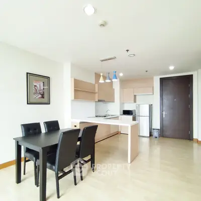 Modern open-layout kitchen with dining area, featuring sleek cabinetry and contemporary lighting.