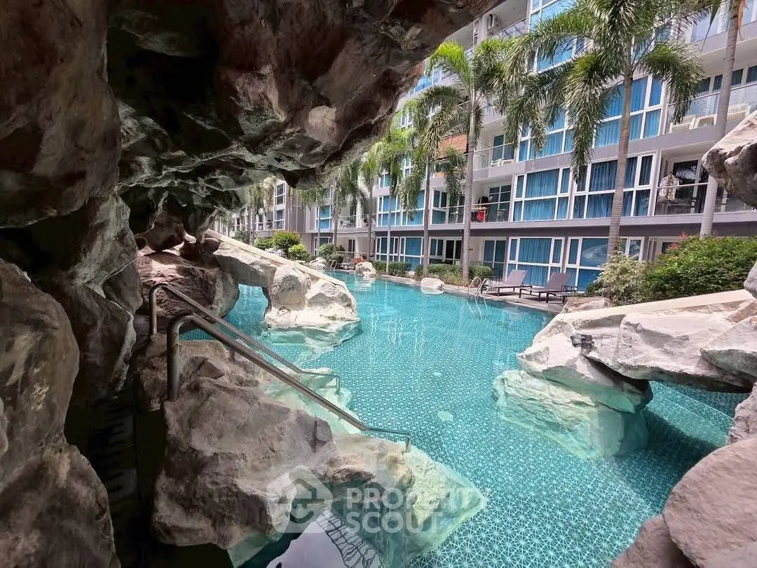 Luxurious pool area with rock formations and modern apartment backdrop.
