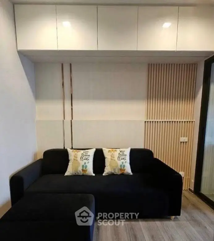 Modern living room with sleek black sofa and stylish wooden paneling