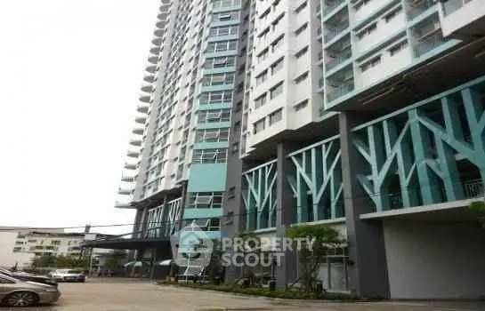 Modern high-rise building exterior with unique architectural design and parking area.