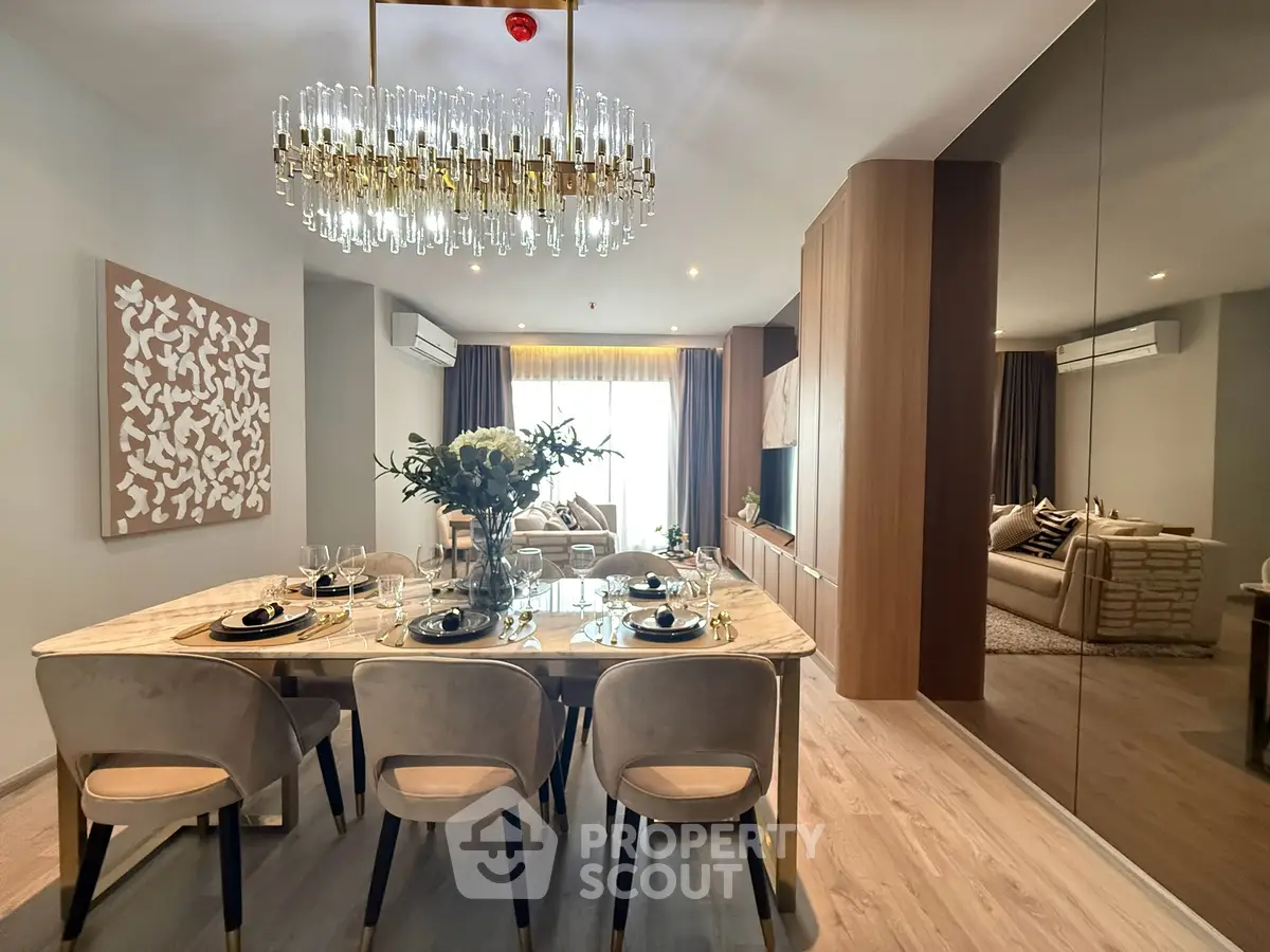 Luxurious open-plan living and dining area with elegant chandelier and modern decor.