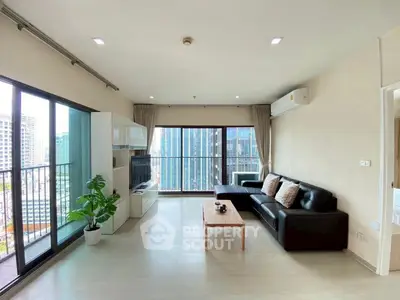 Modern living room with city view, sleek furniture, and large windows in a high-rise apartment.