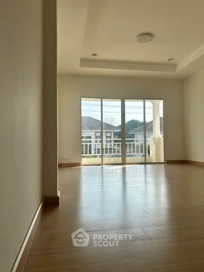 Spacious living room with large windows and wooden flooring, offering a bright and airy atmosphere.