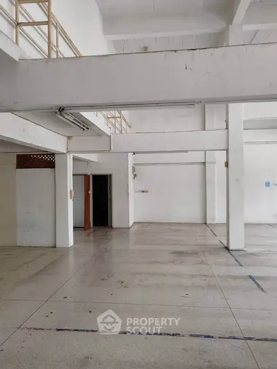 Spacious industrial-style interior with high ceilings and mezzanine level, ideal for creative workspace or studio.