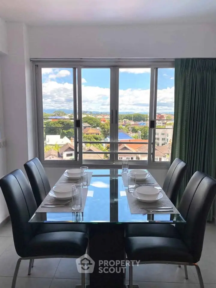 Modern dining area with glass table and stunning city view through large windows.